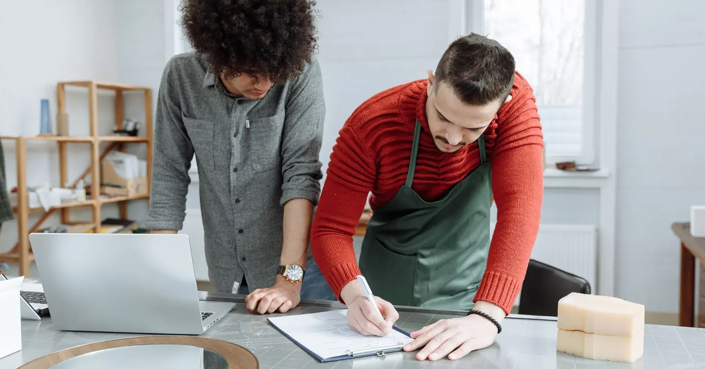 Deux personnes prennent des notes ensemble sur un plan de travail