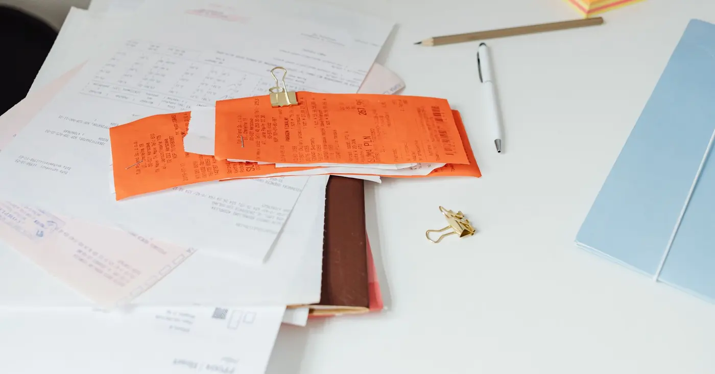 Une pile de tickets et de factures tenue par une pince sur un bureau