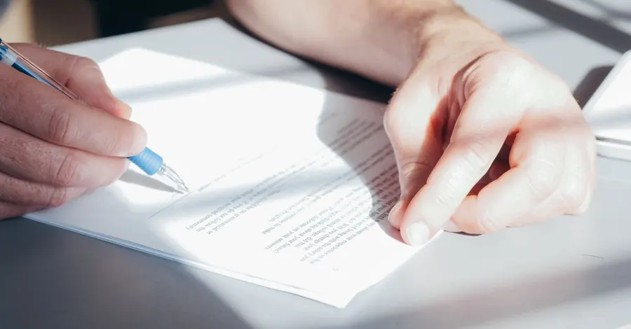 Une main qui signe un contrat sur un bureau