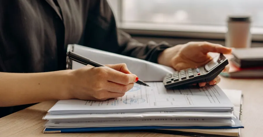 Une personne qui vérifie des documents avec une calculatrice